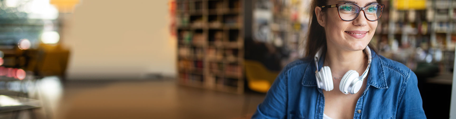 Tienes todo por delante - Chica universitaria con gafas y cascos de música estudiando en la biblioteca Tienes todo por delante - Chica universitaria con gafas y cascos de música estudiando en la biblioteca