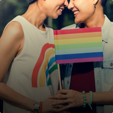 Compromiso con la Igualdad - Una pareja sonriendo mientras sujetan juntas una bandera a favor de la igualdad