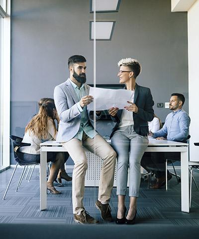 Ventajas para empresas - Dos personas de traje hablando sentados en una sala de reuniones en la oficina