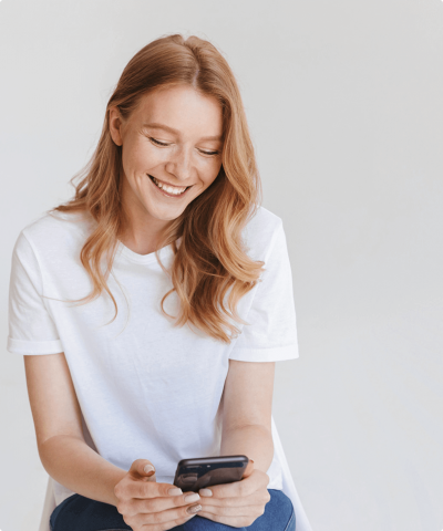 Mujer joven sonriendo mientras busca atención digital de Cajasiete en su móvil