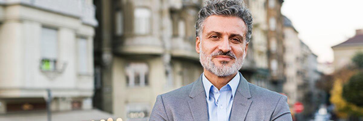 Cuenta Nuestra Gente Empresa - Hombre de negocios con traje y smartwatch con los brazos cruzados en una ciudad Cuenta Nuestra Gente Empresa - Hombre de negocios con traje y smartwatch con los brazos cruzados en una ciudad